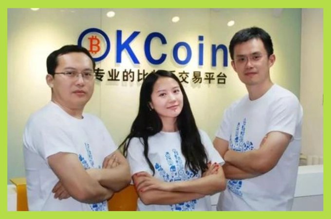 Three people wearing matching white graphic t-shirts stand with crossed arms in front of an 'OKCoin' branded wall featuring Chinese text.