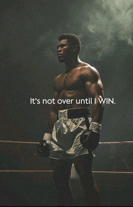 A muscular Black boxer stands in a smoky, dimly lit boxing ring wearing white Everlast trunks and gloves, with the motivational text 'It's not over until I WIN.' overlaid across the image.