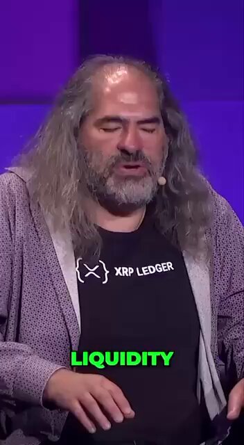 The image features a man with long hair wearing a black shirt, who appears to be giving a speech or presentation. The text "Liquity" can be seen in the image as well. This suggests that the man might be discussing financial matters or sharing insights related to the cryptocurrency market and its impact on the economy.