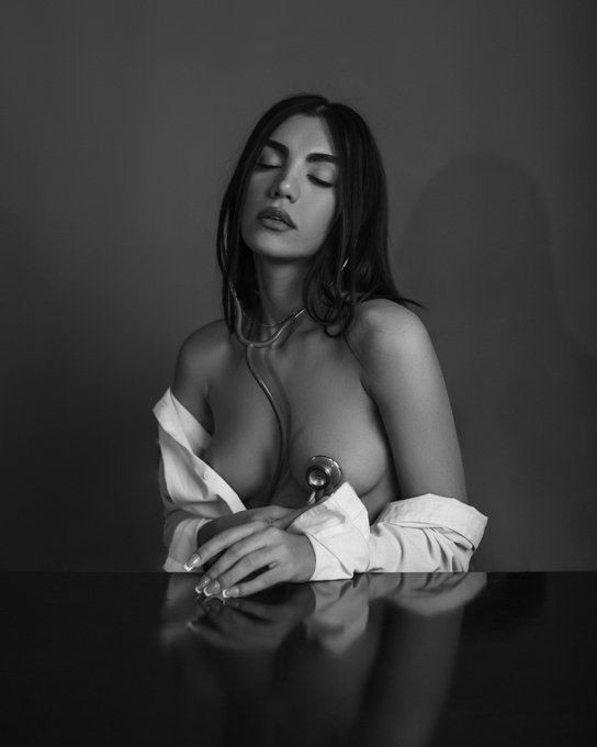 This black and white image shows a woman with a stethoscope around her neck and over her chest, titled "Listen to your heart." The post refers to this artwork being collected by @Alex_NFT_777 as an NFT on objkt.com.