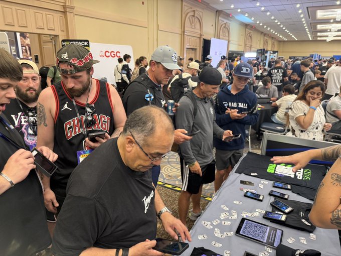 This image captures a lively scene at the @nsccshow with attendees engrossed in their phones, likely celebrating the rip of a rookie Victor Wembanyama card, as mentioned in the post. The presence of the CGC logo also hints at the card grading and collecting aspect of the event.