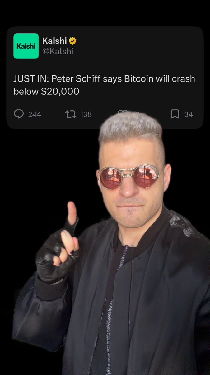 The image features a person with sunglasses and glasses, posing for a photo against a black background. They are wearing a black jacket, which draws attention as they make a finger gesture. The caption of the image includes the text "Just In Peter Schiff says Bitcoin will crash below $20,000". This text seems to be part of a post by a person named Kaki who is likely promoting a product or idea related to Bitcoin.