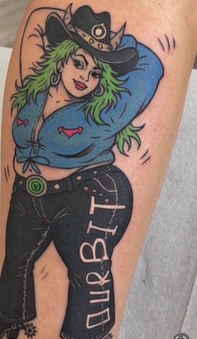 A colorful tattoo on a person's body depicting a stylized cowgirl with green hair, a black hat, blue shirt, and jeans, with the word 'DIRBIT' written down one leg.
