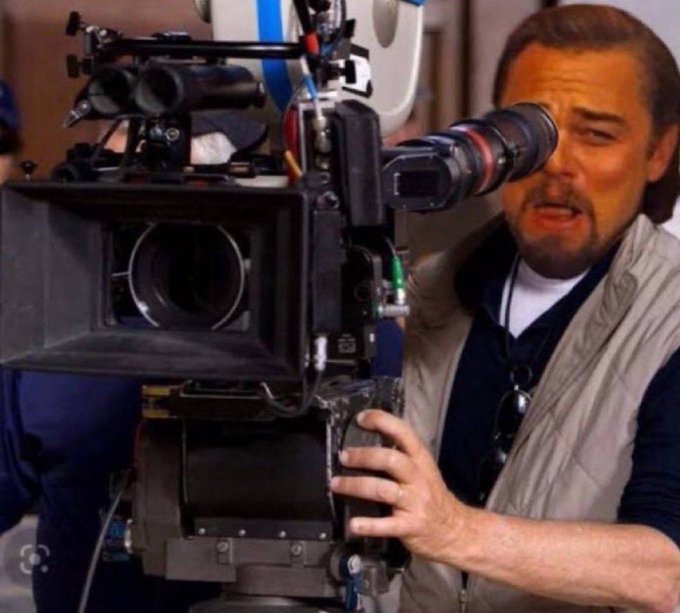 Leonardo DiCaprio peers intensely through a professional film camera, capturing the market as if filming a scene where the Clarity Act stalls and rate hikes are already priced in, suggesting the only direction is upward from here.