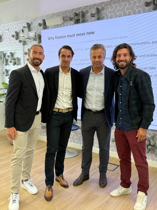 Four men in business casual attire pose together indoors in front of a presentation screen displaying the text "Why finance must move now".