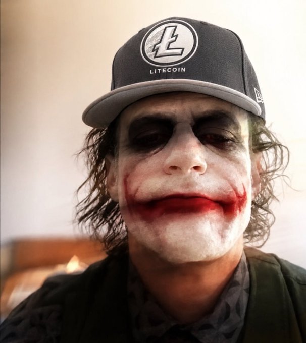 A person wearing the Joker's iconic white face paint and red lip scars wears a black New Era snapback cap with the Litecoin logo and "LITECOIN" text.