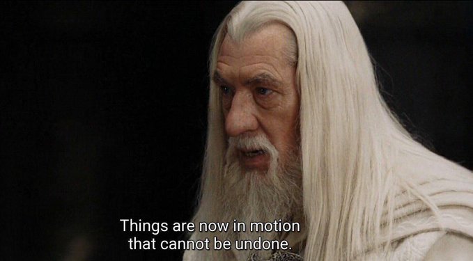 A close-up of an older man with long white hair and a white beard wearing white robes against a dark background. Subtitle reads: "Things are now in motion that cannot be undone."