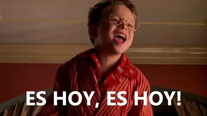 A young boy with glasses, wearing a red striped pajama shirt, laughs hysterically with the Spanish text 'ES HOY, ES HOY!' (It's today, it's today!) overlaid at the bottom.