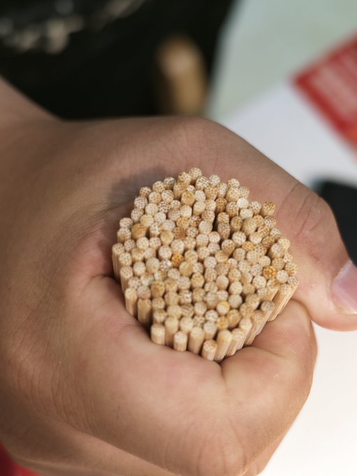 A close-up shows a hand holding a small bundle of wooden toothpicks.