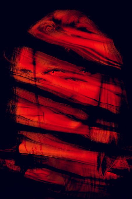 The image features an abstract portrait of a woman with red hair, partially obscured by black lines that create a sense of mystery or intrigue. The background appears to be dark, which further emphasizes the focus on the subject's face. The caption "P a s s i n g T h r o u g h 44 tezos" suggests that this image is part of a larger series or collection and might be related to a specific theme or artistic concept.