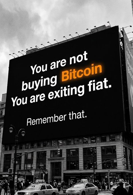A large billboard overlooking a busy city street displays the message "You are not buying Bitcoin. You are exiting fiat. Remember that." with "Bitcoin" highlighted in orange, reinforcing the post's urgent call to invest in Bitcoin before missing out. The dramatic black-and-white cityscape amplifies the advertisement's bold financial warning.
