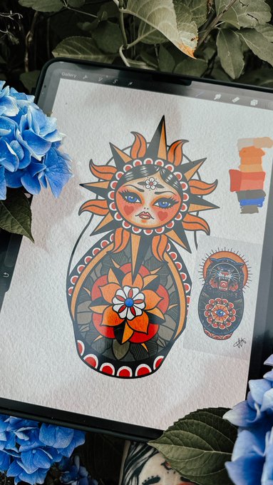 A digital illustration of a Matryoshka doll featuring a sun-faced woman in orange and red tones, displayed on a tablet screen surrounded by blue hydrangea flowers.