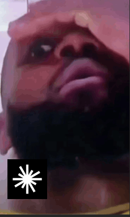 A low-resolution animated GIF showing a stylized face with reddish tones looking upward, with a black square containing a white starburst/spinner loading icon in the bottom-left corner.