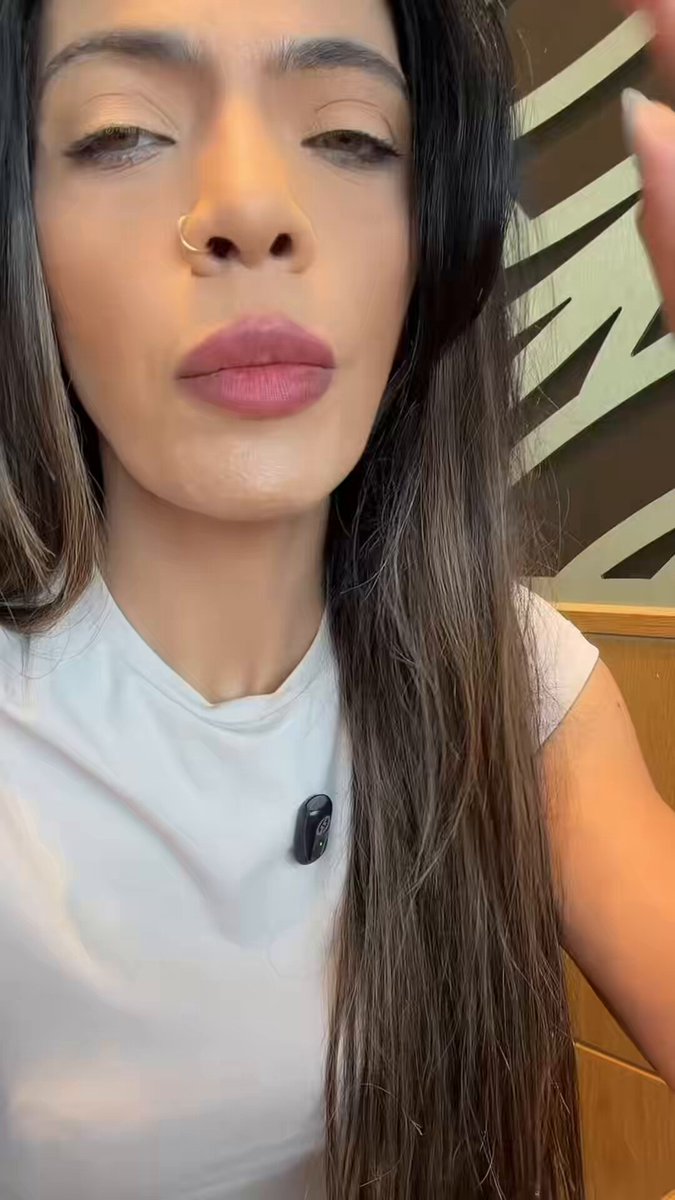 The image features a woman with long brown hair wearing a white shirt. She has her hand on her head as if she's thinking or pondering something. The background of the image includes a green sign, which could be related to Bitcoin or another topic being discussed in the post.