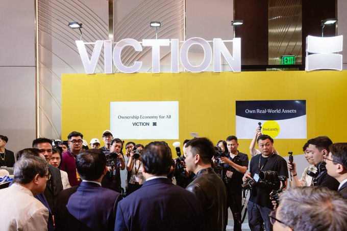 A crowd gathers at a 'VICTION' booth with signage reading 'Ownership Economy for All' and 'Own Real-World Assets,' surrounded by photographers and onlookers.
