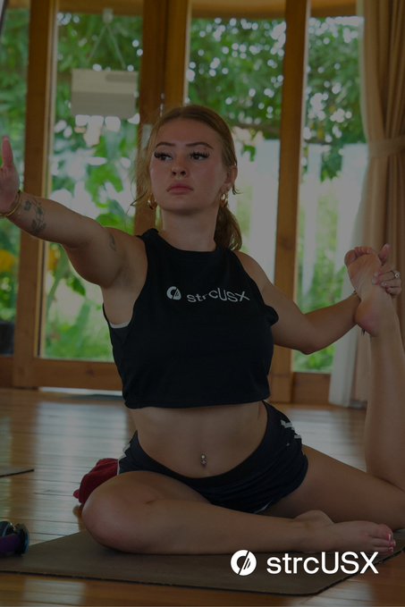 A woman in a black "strcUSX" cropped tank top and shorts performs a seated yoga pose on a mat, with large windows and greenery in the background. The "strcUSX" branding is also displayed in the lower right corner, tying the imagery to the post's message about accessible, structured credit coming soon.