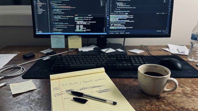 A developer's workspace showing a monitor displaying code, a keyboard, a coffee mug, sticky notes, and a notepad with handwritten notes including 'ZK Proofs > OPoAI quorums'.