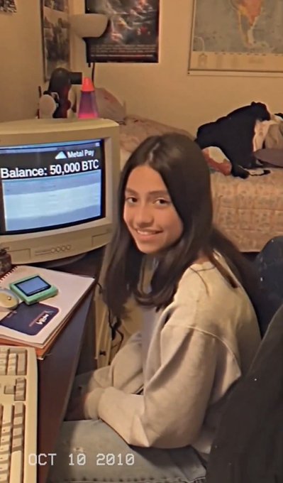 A vintage photograph dated October 10, 2010, showing a young woman sitting in front of an old CRT screen displaying 'Balance: 50,000 BTC' on what appears to be a Metal Pay transaction page.
