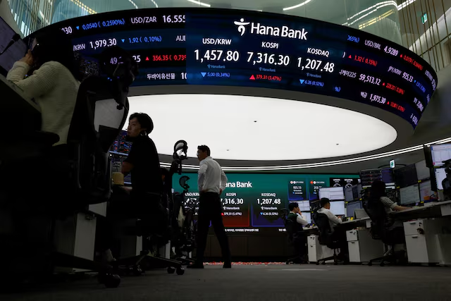 A trading floor at Hana Bank with large electronic boards displaying currency exchange rates (USD/ZAR, USD/KRW, etc.) and stock indices like KOSPI and KOSDAQ, while several traders work at their desks.