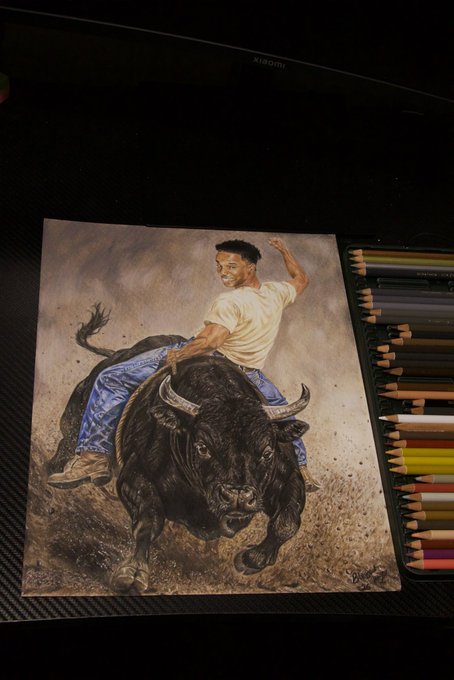 A detailed colored pencil drawing of a cowboy riding a charging bull is displayed on a desk next to a row of colored pencils, with "XIAOMI" visible on a monitor in the background, representing the artist's 169 hours of dedicated work created as a tribute to @blknoiz06.