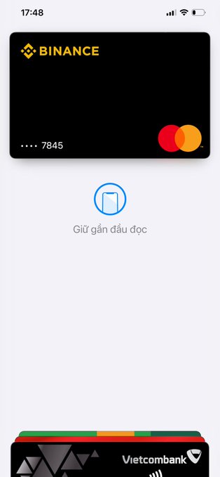 A mobile wallet screenshot showing a Binance debit card with Mastercard logo and a VCB (Vietcombank) card, with Vietnamese text 'Giữ gần đầu đọc'.