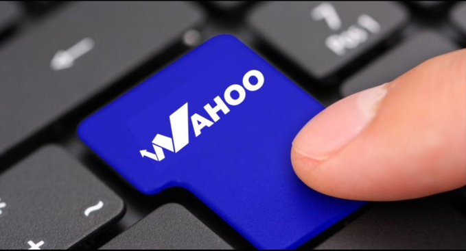 A finger presses down on a blue keyboard key displaying the white "YAHOO" logo, set against a black keyboard background.