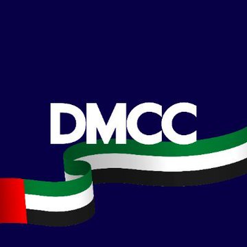 The image features a blue background with a large white "DMC" logo at the center of the frame. The logo is accompanied by a green, red, and black striped flag that extends across the entire width of the image. Below the logo, there's text that reads "BIG NEWS: Dubai'S DMCC and Tether ($USDT) join forces to expand blockchain infrastructure, digital assets, and tokenized finance." The combination of the logo and the accompanying text suggests a connection between the Dubai DMCC and Tether, possibly indicating their collaboration in expanding the blockchain infrastructure or introducing new financial products.