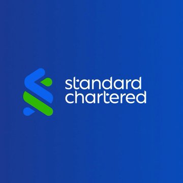 The image displays the Standard Chartered logo, featuring a stylized blue and green "S" symbol alongside the company name in white text on a blue background. The logo directly represents the bank referenced in the accompanying post, which cites Standard Chartered's bullish forecast for Ethena's USDe stablecoin and ENA token.