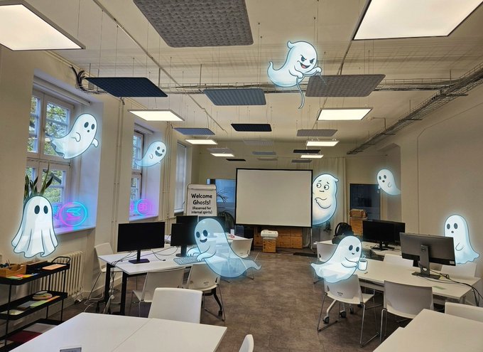 A room decorated with multiple animated ghost stickers overlaid on the image, featuring desks, computers, and a 'Welcome Ghosts!' sign.