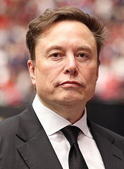 A man in a dark suit and black tie stands against a blurred background, his expression serious. The image accompanies news about Elon Musk's dual presence in the Nasdaq-100, as SpaceX joins Tesla in the index with the two companies collectively holding 30,221 bitcoins.