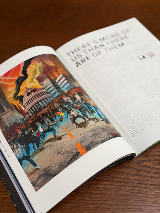 An open art book displaying a colorful illustration of a chaotic scene with figures and the U.S. Capitol building, accompanied by the heading 'THERE'S MORE OF US THAN THERE ARE OF THEM'.