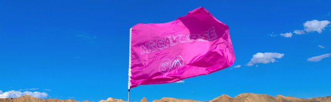 A bright pink flag with 'NO GAMERS' text and a logo waving against a blue sky with mountains in the background.