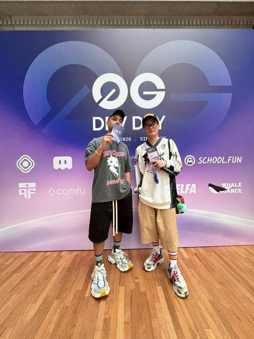 Two young men pose at the 0G (Zero Gravity) event backdrop in Singapore, with visible sponsor logos including School.Fun, Comfy, and Whale Dance, while the post confirms their role as media partners for the 0G Labs and FastX events during their trip from Malaysia.