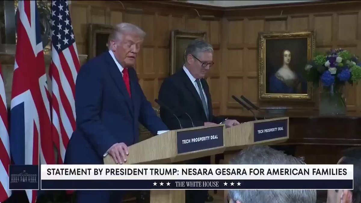 The image shows two men standing at a podium with microphones, giving a speech or addressing an audience. The text "Statement by President Trump" can be seen near them, indicating that they are speaking about a particular topic. There is also a person in the background who appears to be listening to their speech.