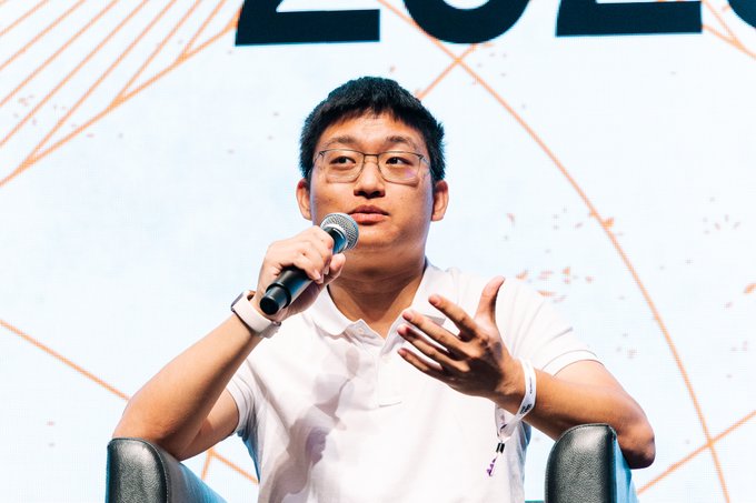 A man wearing glasses and a white polo shirt speaks into a microphone while gesturing with his hand, appearing to be on stage at a conference event.

The image appears to show Charles Lu, co-founder mentioned in the post, speaking at Korea Blockchain Week in Seoul, likely during the L2 adoption panel discussion referenced in the accompanying text.