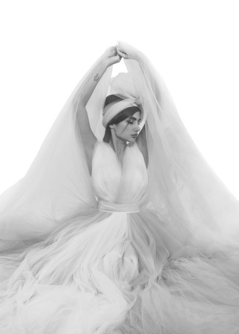 A woman in a flowing white gown and veil poses gracefully with her arms raised overhead, set against a stark white background. The ethereal, high-fashion bridal aesthetic of the artwork likely reflects the artist's appreciation to a collector and gallery, celebrating a secondary market acquisition of this elegant piece.