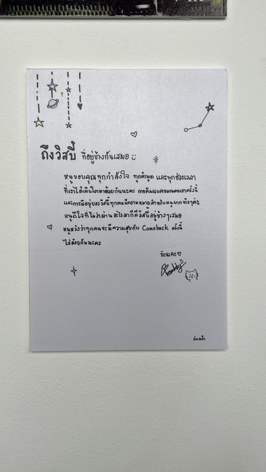 A handwritten Thai letter/note on light purple paper with cute doodles of stars, hearts, and constellations. The text addresses 'พี่ริว' and mentions sending a love letter via comeback, signed by 'น้องบี'.