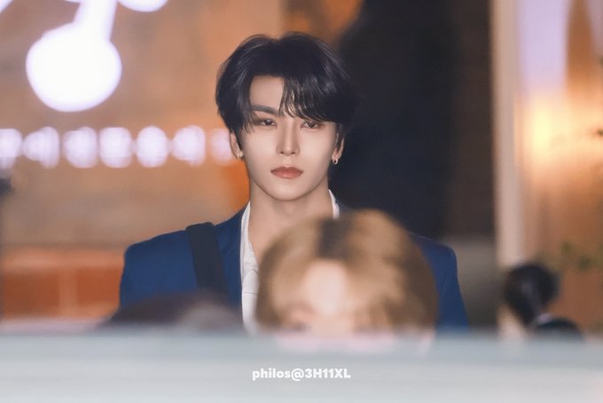 A man with dark hair wearing a blue blazer looks forward in a dimly lit setting, with the watermark 'philos@3H11XL' visible at the bottom.