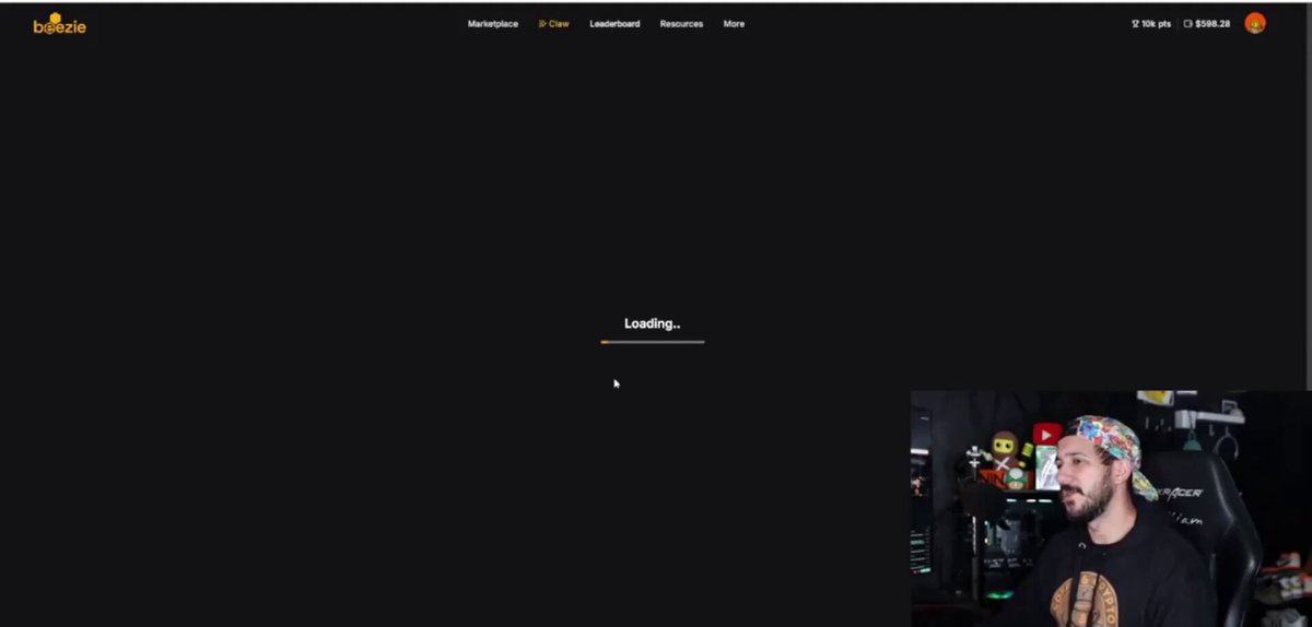 The image shows a man sitting down with a computer screen displaying a webpage that says "loading" or "loading up", possibly indicating that he is waiting for something to load, such as a video game or an online shopping cart. The background of the image is black and has a white border, giving it a minimalist appearance. There are no other objects in the scene besides the man sitting at his computer.