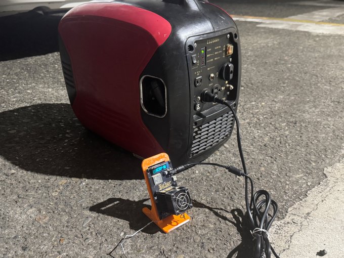 A photograph of a red and black portable power generator on asphalt, with an orange electronic device (labeled 'BIGB') connected via cables, likely used for Bitcoin mining.