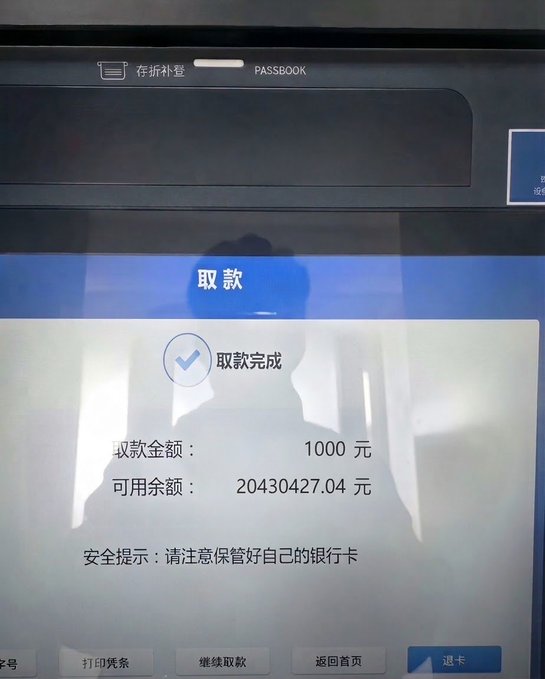 An ATM/Passbook screen in Chinese showing a successful withdrawal (取款完成) of 1000 yuan with an available balance of 2,043,0427.04 yuan.