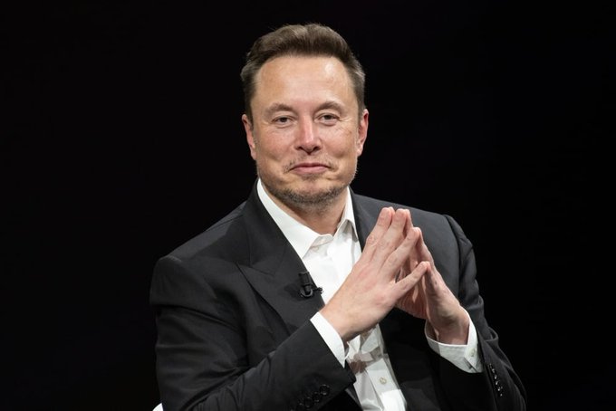 The image features a man wearing a suit, standing and giving hand claps, which seem to be an expression of excitement or joy related to space exploration. The caption of the accompanying post implies that the company's shares are likely on an upward trajectory with "SpaceX bulls surge 10% pre-market." This indicates strong interest in the success of SpaceX, a private aerospace manufacturer. As the man is dressed in a suit and giving hand claps, it might be inferred that he has a positive view about the future of space exploration or the company's achievements.