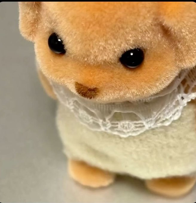 A close-up of a Sylvanian Families/Calico Critters plush rabbit figure wearing a white lace dress.