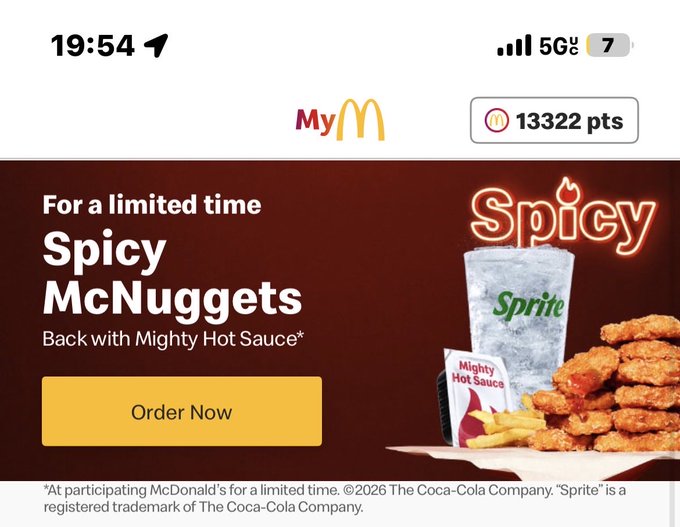 Mobile screenshot of the MyMcDonald's app displaying a promotional banner for 'Spicy McNuggets' with Mighty Hot Sauce, featuring an image of the nuggets alongside a Sprite cup and Mighty Hot Sauce packet, with an 'Order Now' button.