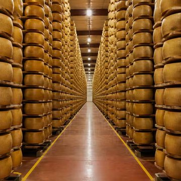 Rows upon rows of large cheese wheels stacked high in a warehouse aisle, visually illustrating the post's quip about Bitcoin not being made of cheese—juxtaposing the traditional, inflation-prone commodity with the digital asset being championed.