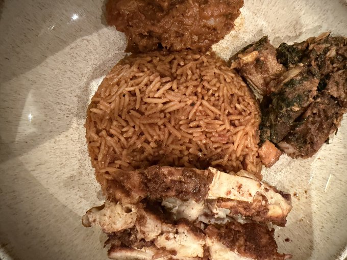 A plate of home-cooked comfort food featuring seasoned red rice, saucy meat, stewed greens, and what appears to be roasted chicken or turkey — the playful caption "Who made this for you?!! Lmaoo" suggests the meal looks so good it jokingly demands to know who the lucky cook was.