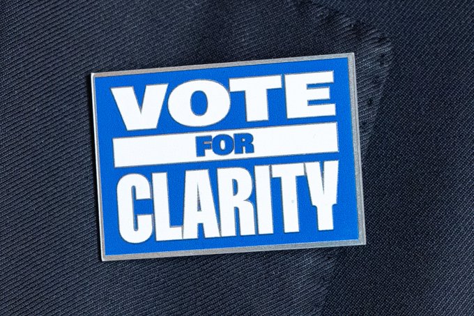 A blue and white "VOTE FOR CLARITY" sticker is displayed on a dark blue fabric, likely a suit jacket. The image supports the post's call to action urging Americans to contact their senators ahead of the September 15 vote on crypto legislation, emphasizing the need for clear regulatory rules to make America the "crypto capital of the world."