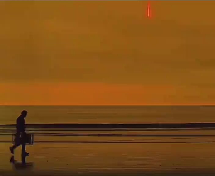 The image shows a man walking along a beach at sunset with his suitcase. The sky has an orange hue, creating a beautiful backdrop for the scene. The man appears to be contemplating something or simply enjoying the view as he walks. The photo is captioned "First non 6-figure month since September 2025 was my sign to walk away. Forever grateful for @Pumpfun for making me a millionaire but I think this is where we take a breather and wait."