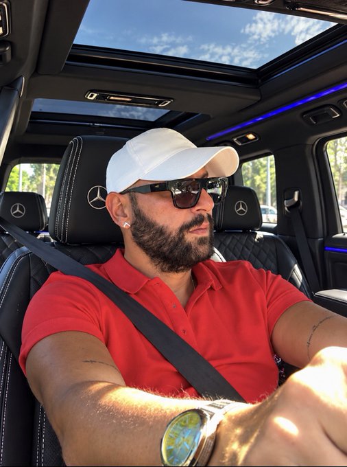 A man wearing a white cap, sunglasses, and a red polo shirt drives a Mercedes-Benz with a panoramic sunroof, projecting a confident, affluent vibe. The image visually reinforces the post's giveaway by pairing the text with a stylish image of luxury and success, suggesting the poster is a credible, high-status figure ready to send $SOL to lucky winners.