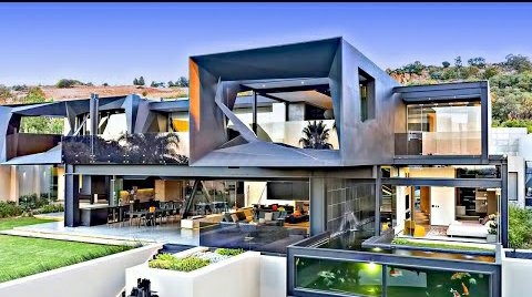 A large modern luxury home featuring angular contemporary architecture with expansive glass windows and an outdoor pool area.